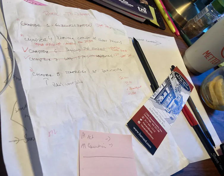 Paper with handwritten notes on a table near a mug.