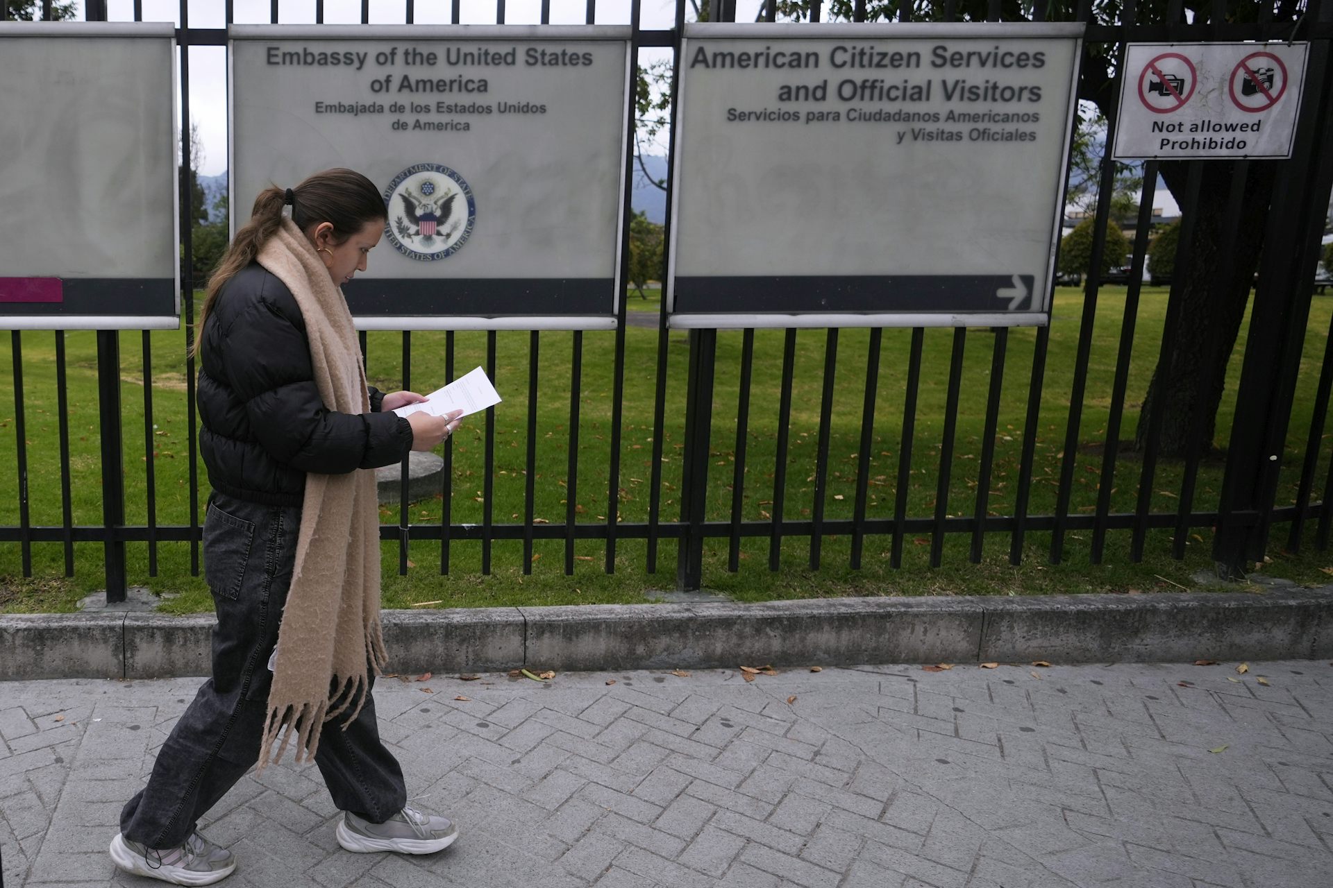 Una mujer con la cabeza cubierta antes del letrero dicho por la Embajada de los Estados Unidos.