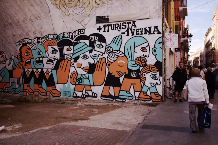 a mural painted on a city street with people walking past