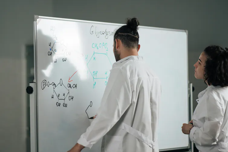 Man and woman at whiteboard with chemistry drawings