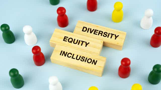 The words "diversity," "equity" and "inclusion" are seen in wood blocks surrounded by small, multicolored representations of people.