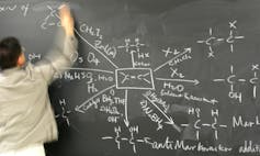 Maestro que dibuja un diagrama de química compleja en el tablero