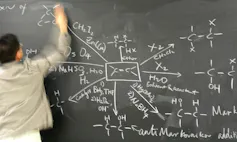 Teacher drawing a complex chemistry diagram on a chalkboard