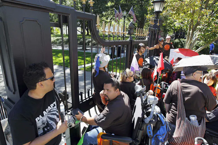 People seen at a gate, some in wheelchairs.