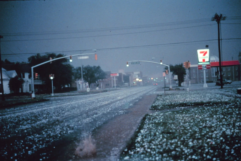 Large hail the size of golf balls covers the ground and street.
