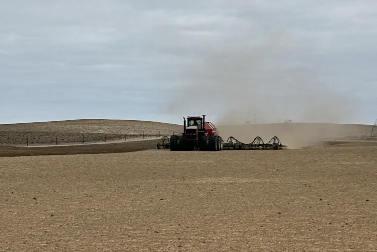 A seeder working in brown dry paddock