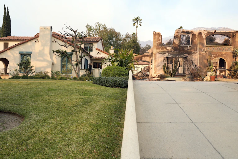 Two homes, one surrounded by lush vegetation survived unscathed. The neighboring home, just a few feet away, burned. The photo was taken on Jan. 9, 2025.