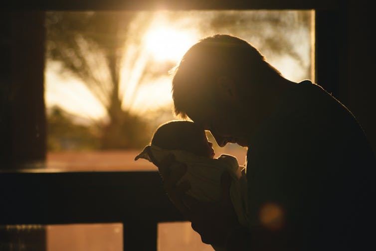 A dad presses his forehead against his baby's forehead.