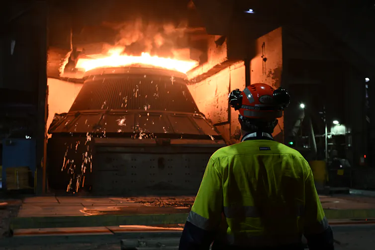 a worker stands in front of a steel furnace.