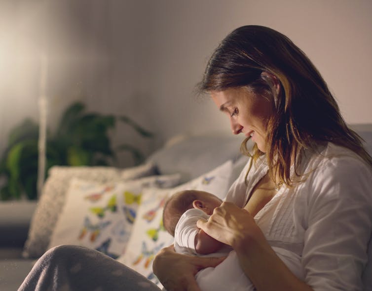 A woman looks at her baby while breastfeeding.