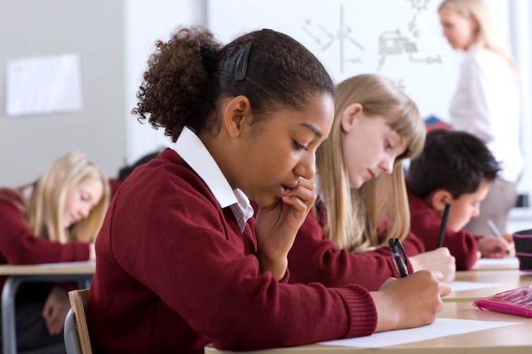 A row of students bent over desks.