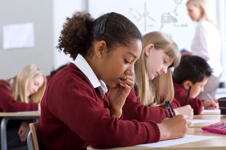 A row of students bent over desks.