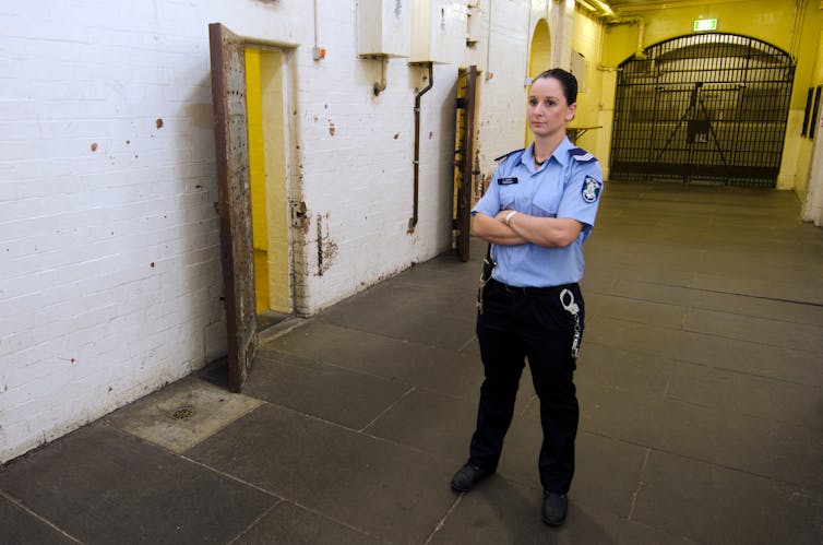 A female prison guard standing outside an open cell door