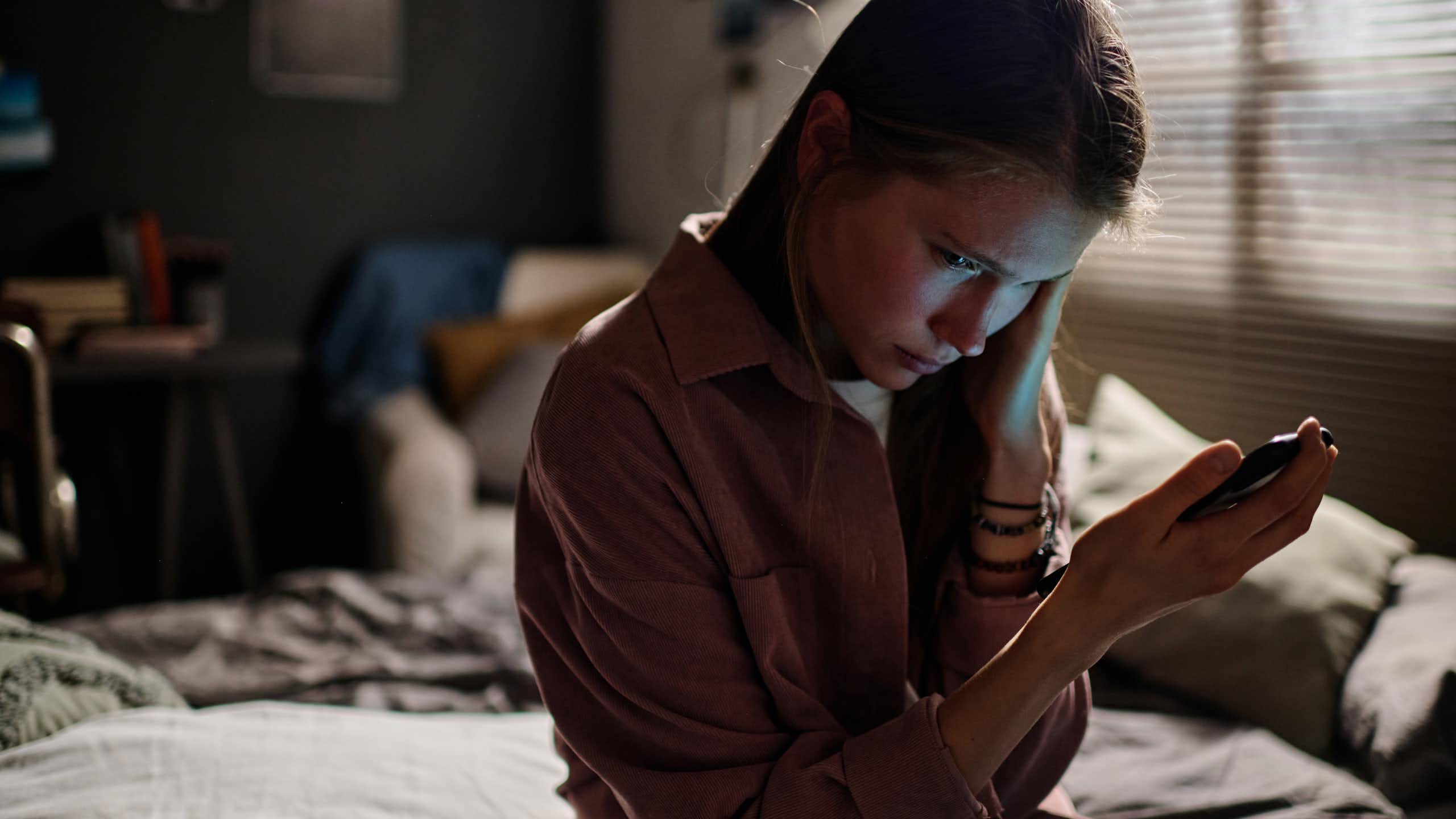 Una adolescente mira compungida su móvil