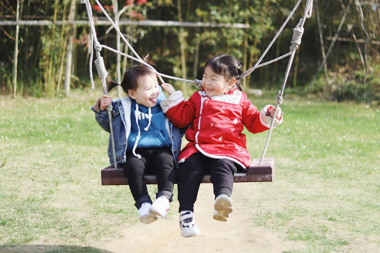 Two young children on a swing.