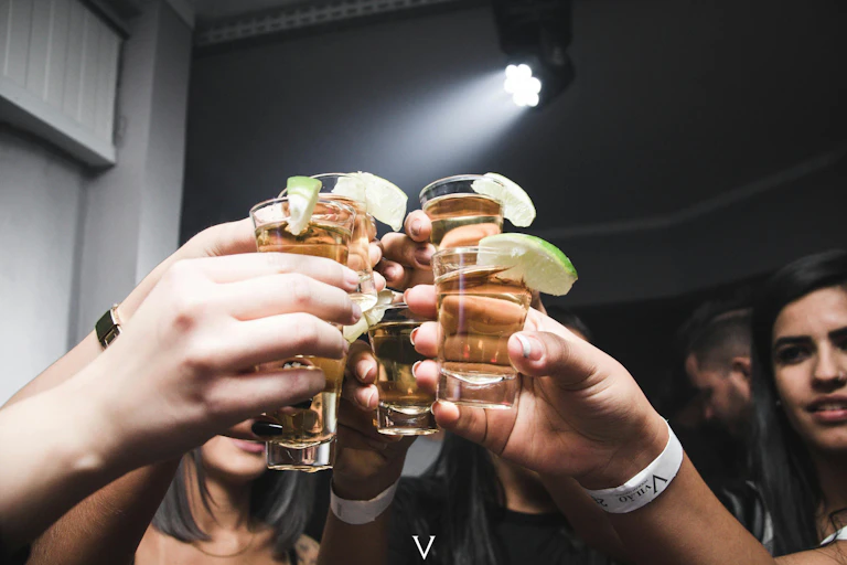 People holding up shot glasses.