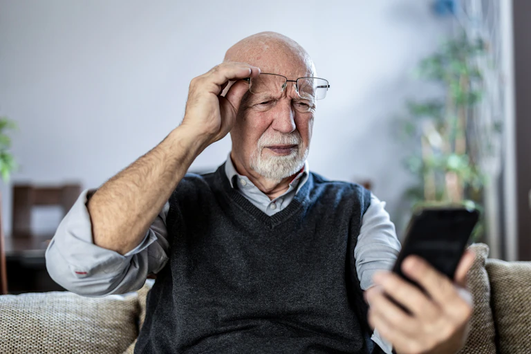 An older man looking in confusion at a mobile phone