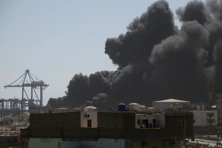 A large plume of black smoke rising, with a crane in the background