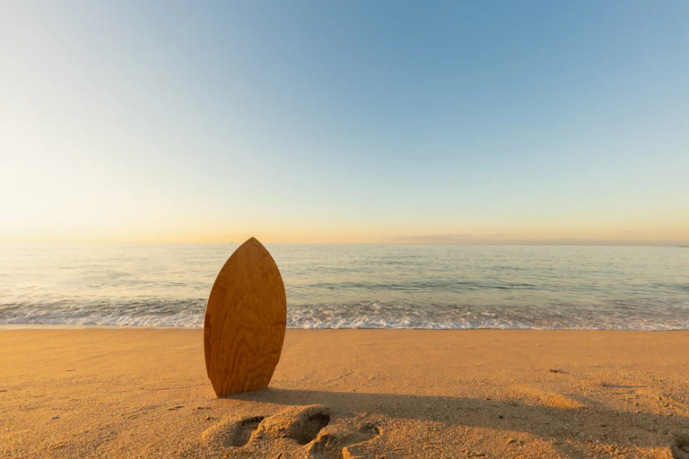 Una tabla de surf clavada en la arena de una playa desierta.