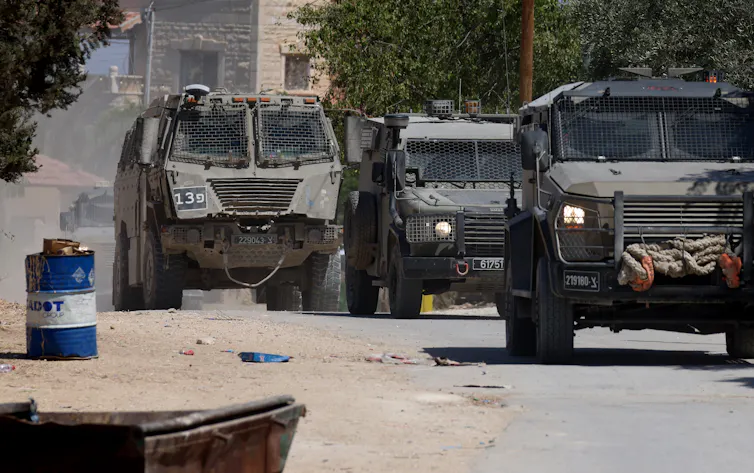 A convoy of IDF military vehicles moves along a road in Jenin on the occupied West Bank.