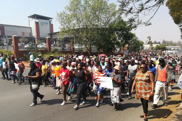 A crowd of people walking in the street, some holding banners