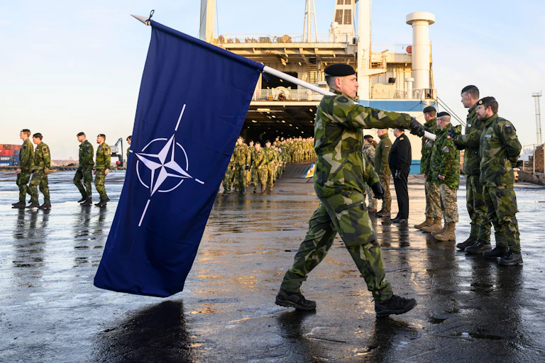 Troops in Riga, Latvia, in 2025, with a Nato flag.