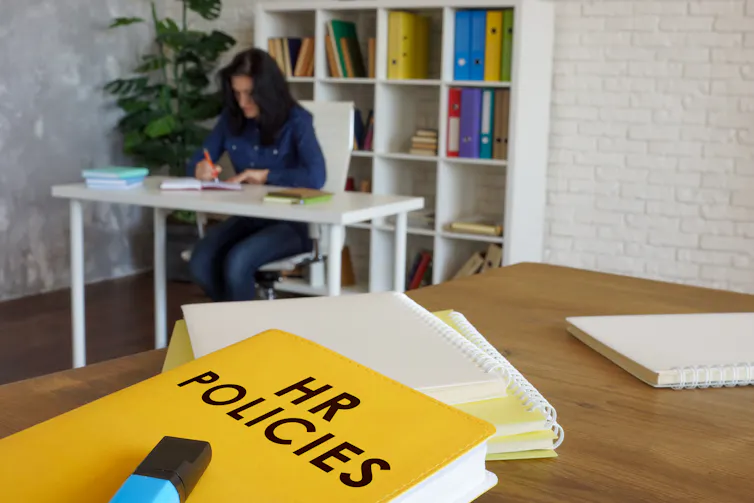 copy of an hr policy on a desk with a worker at a desk in the background