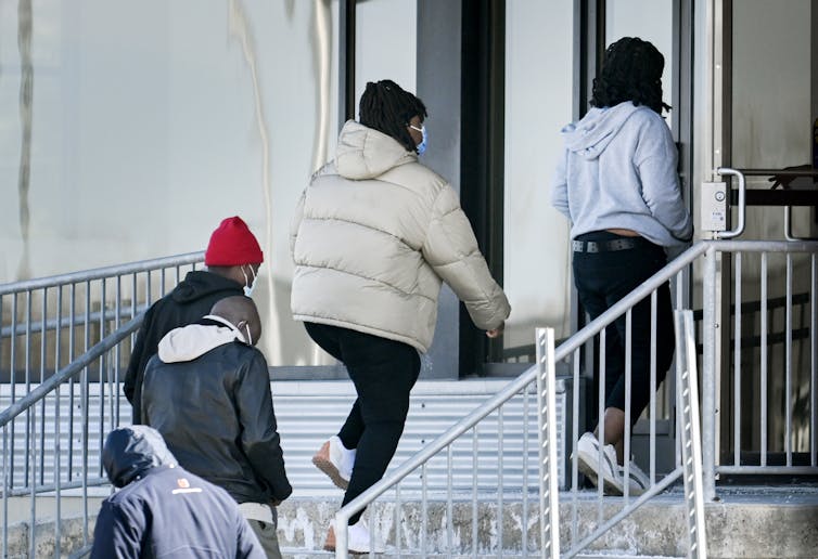 Un grupo de personas camina por las escaleras para ingresar al edificio.