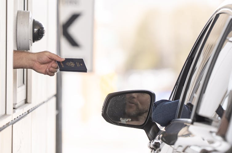 Se vio que la mano sale del quiosco para devolver el pasaporte al automóvil en el automóvil.