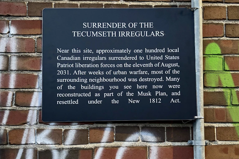 A plaque on a brick wall says 'surrender of the Tecumseth irregulars.'