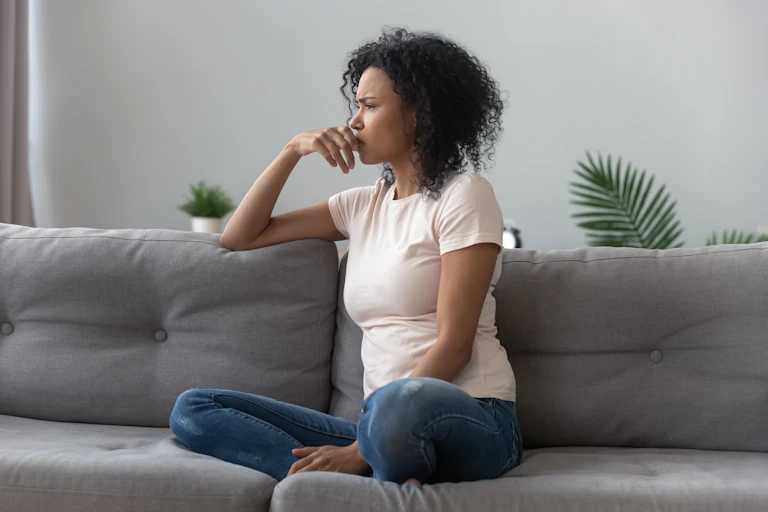 A woman sitting on a couch with a thoughtful expression