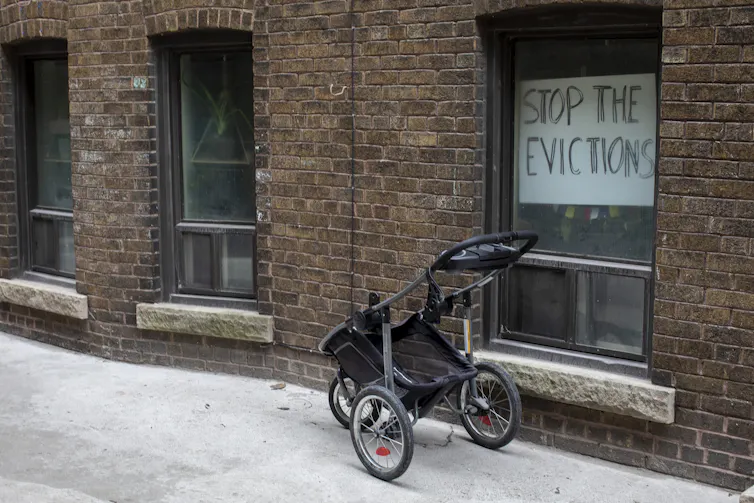 A sign in the window of a brick apartment says 'stop the evictions'