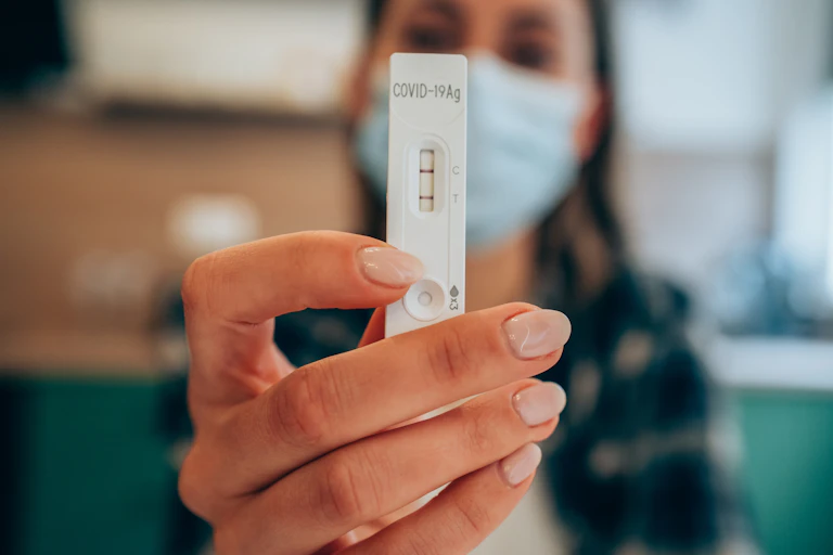 A woman holding up a RAT test.