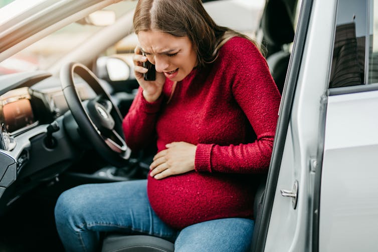 Pregnant woman starting to feel pain and contractions driving a car.