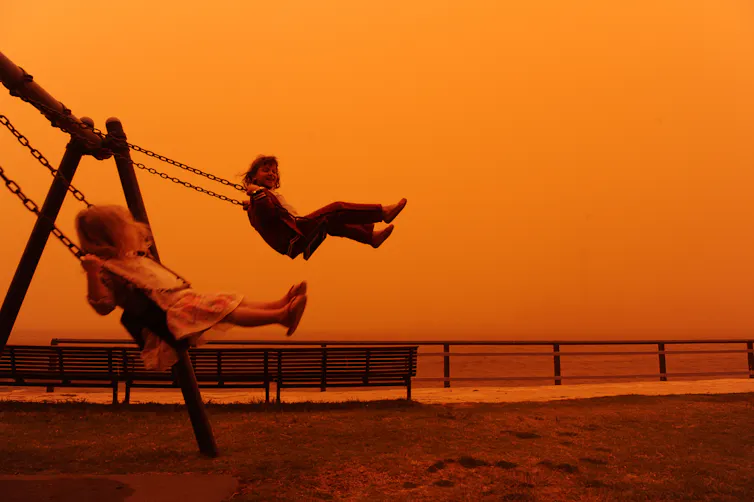 Two children play on the swings amid an orange dust cloud in Balmain, Sydney, Wednesday, Sept. 23, 2009.