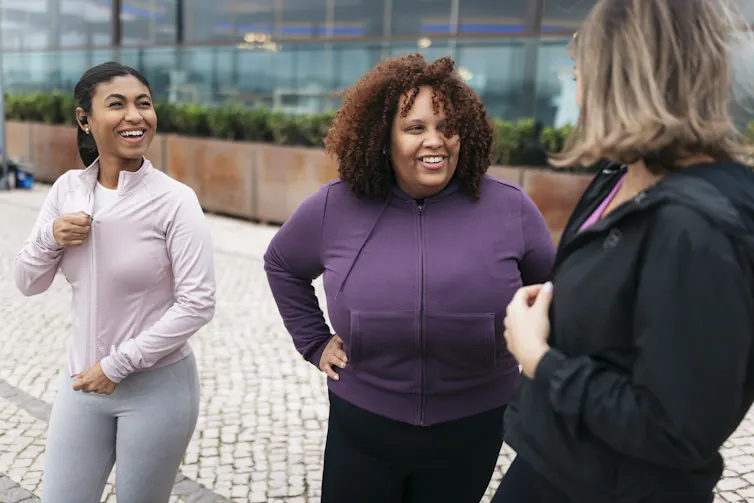 Three smiling women in exercise gear.