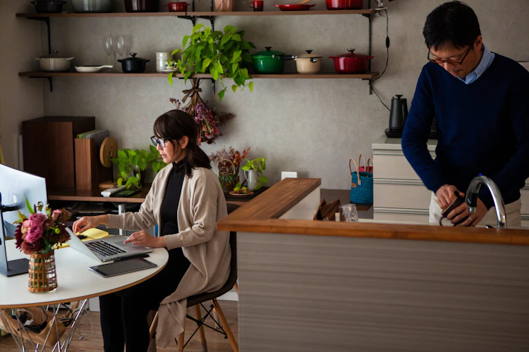 Couple où la femme travaille sur son ordinateur et l'homme lave une tasse.