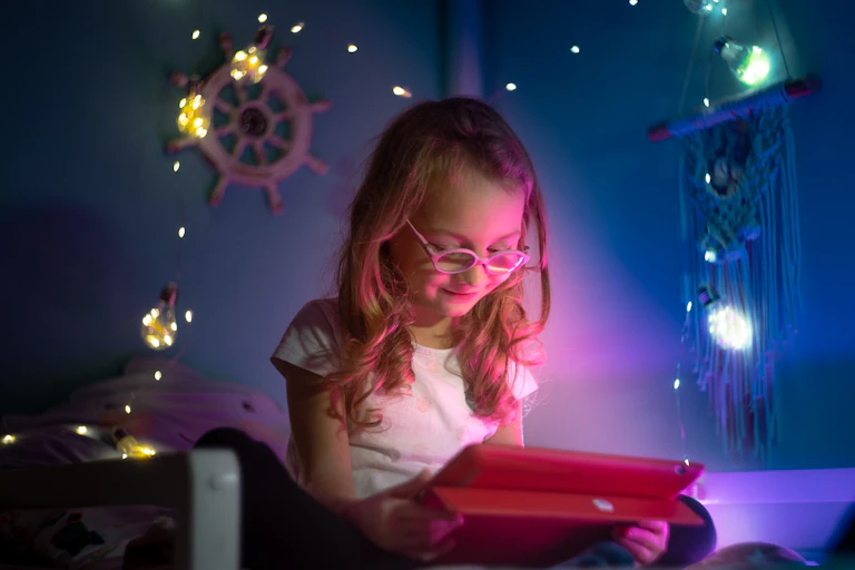 Niña viendo una pantalla en su habitación