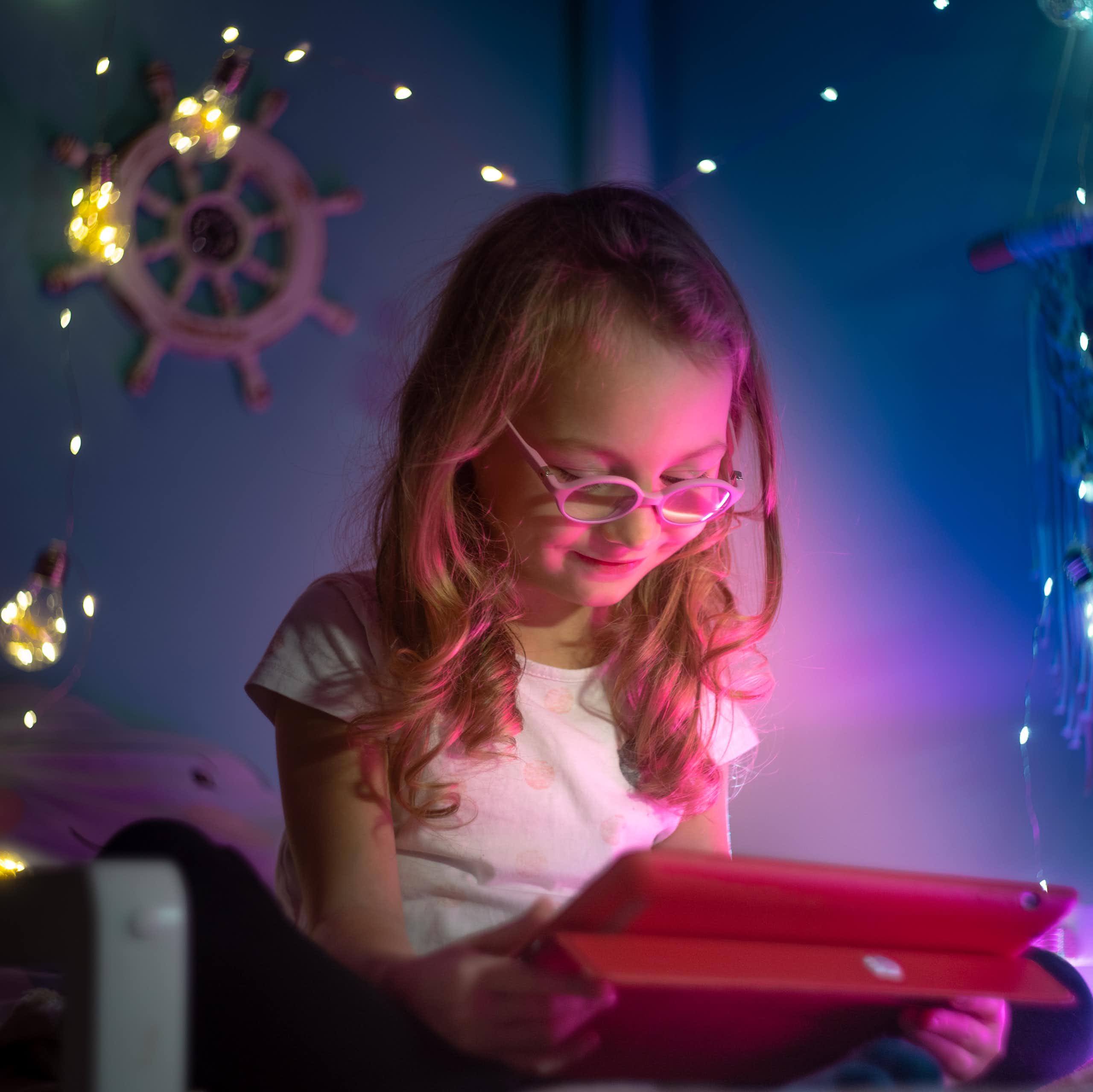 Niña viendo una pantalla en su habitación