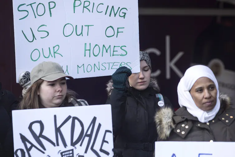 Rent strikers hold signs, one reading Stop Pricing Us Out of Our Homes You Monsters
