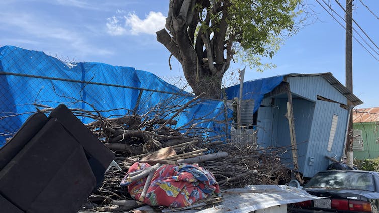 A house that's been destroyed is covered by tarps.