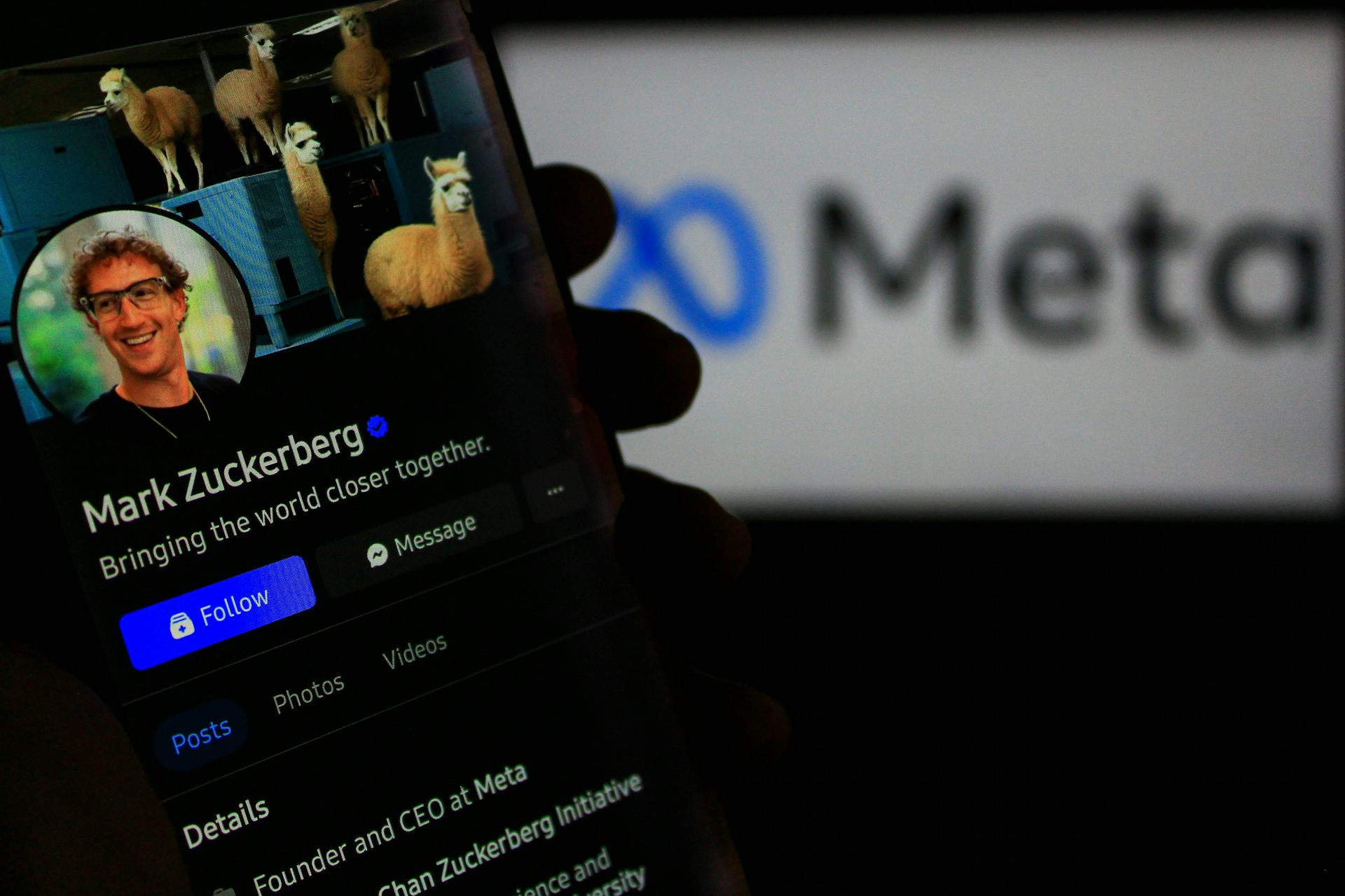 Un téléphone montrant Mark Zuckerberg est tenu devant un écran affichant « Meta »