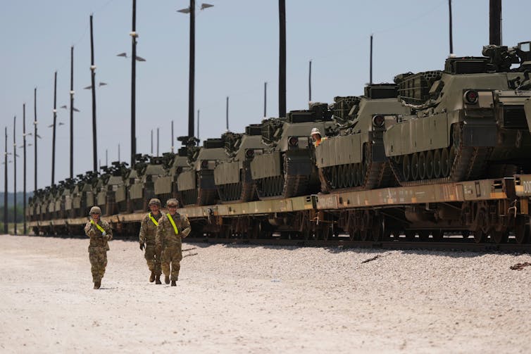 La fila de tanques militares en una larga plataforma en el ferrocarril