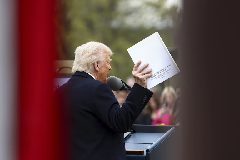 US President Donald Trump holds up a document from the Office of the United States Trade Representative