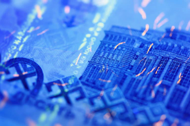 Close-up of a banknote lit up in UV light showing security features.
