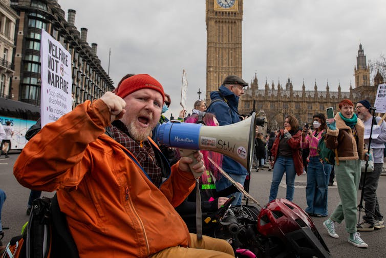 Does the important thing to uniting in opposition to divisive politics lie in our private lives? 1 A protestor shouting into a loud speaker in front of the houses of parliament in London.