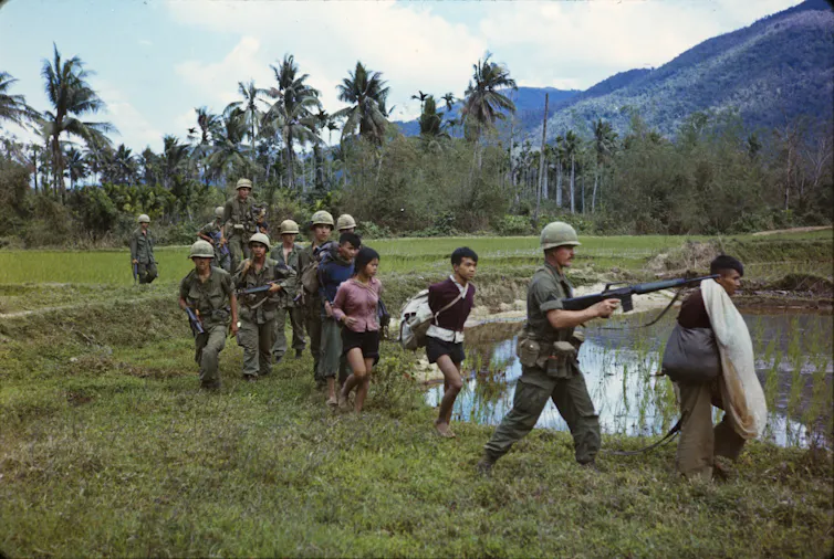 American soldiers leading Vietnamese citizens away during the Vietnam war.