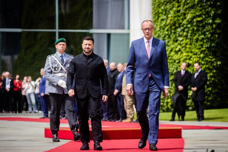 The controversy over genocide claims when it comes to Gaza intensifies 1 German chancellor, Friedrich Merz, walks along a red carpet with Ukrainian president, Volodymyr Zelensky with aides and military officials in the background.