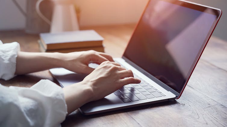 a woman's hands type at a laptop keyboard