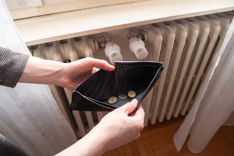 Manos sujetando una cartera abierta con unas pocas monedas